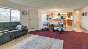 A living room with a grey sofa, two patterned armchairs, a red rug, and a clock on the wall. - Family-friendly Winston Vacation Rental w/ Deck! (Winston)