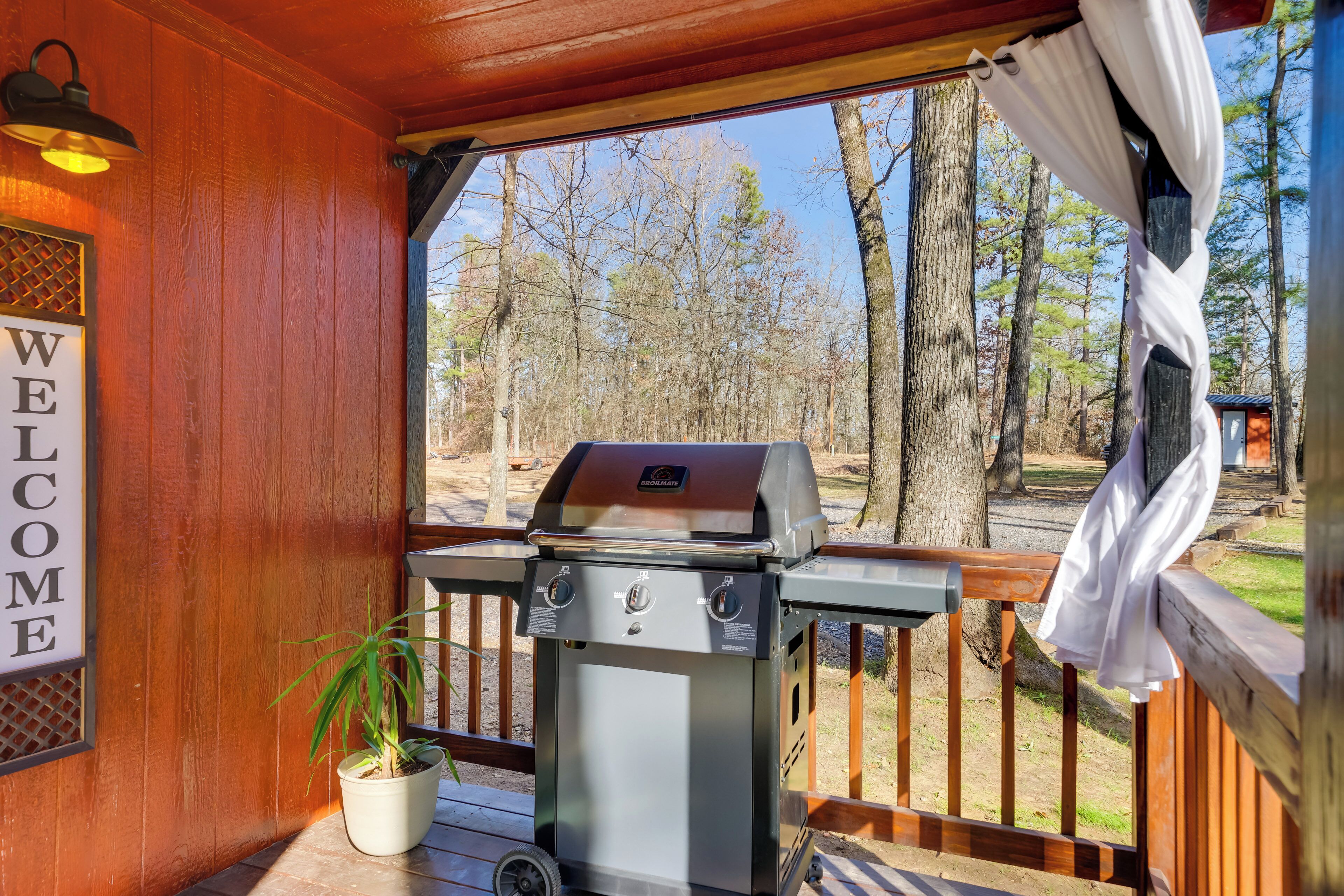 A wooden deck with a barbecue grill, a welcome sign, and a potted plant.