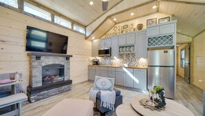 A cozy cabin interior with a stone fireplace, a flat-screen TV, a kitchen with modern appliances, and a comfortable seating area. - 'sweet Spot' Cabin in Broken Bow w/ Fire Pit! (Broken Bow)