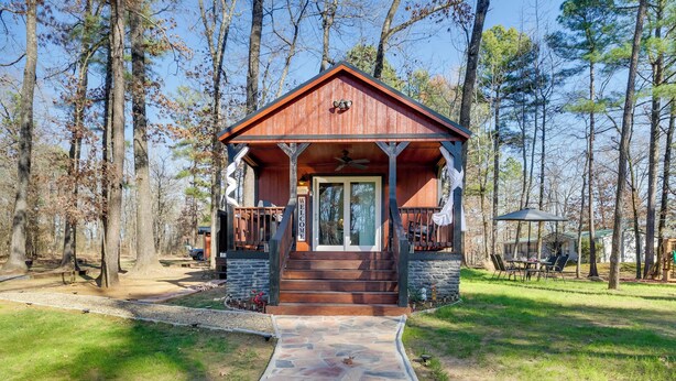 Une cabane en bois avec un chemin de pierres menant à l’entrée, entourée d’arbres.