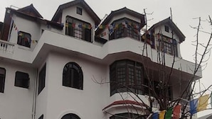 A multi-story building with balconies, arched windows, and a tree with colorful flags. - Hotel Silverine Srinagar (Srinagar)
