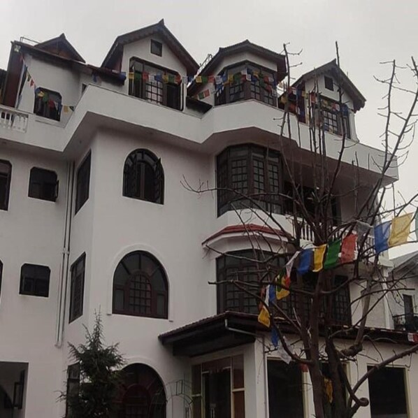 A multi-story building with balconies, arched windows, and a tree with colorful flags. - Hotel Silverine Srinagar (Srinagar)