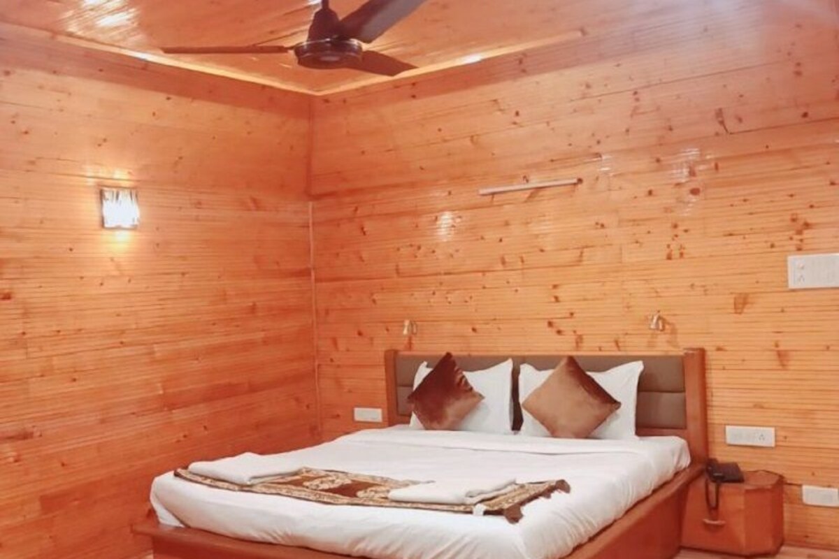 A wooden room with a bed, a ceiling fan, and a nightstand.