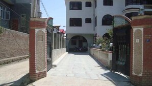 A narrow alleyway with a gated entrance leading to a building with multiple windows and a covered entrance. - Hotel Silverine Srinagar (Srinagar)
