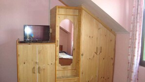 A wooden wardrobe with a television on top, a mirror, and a window with curtains. - Hotel Silverine Srinagar (Srinagar)