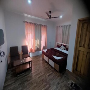 A room with a bed, a desk, two chairs, a ceiling fan, and curtains. - Hotel Silverine Srinagar (Srinagar)