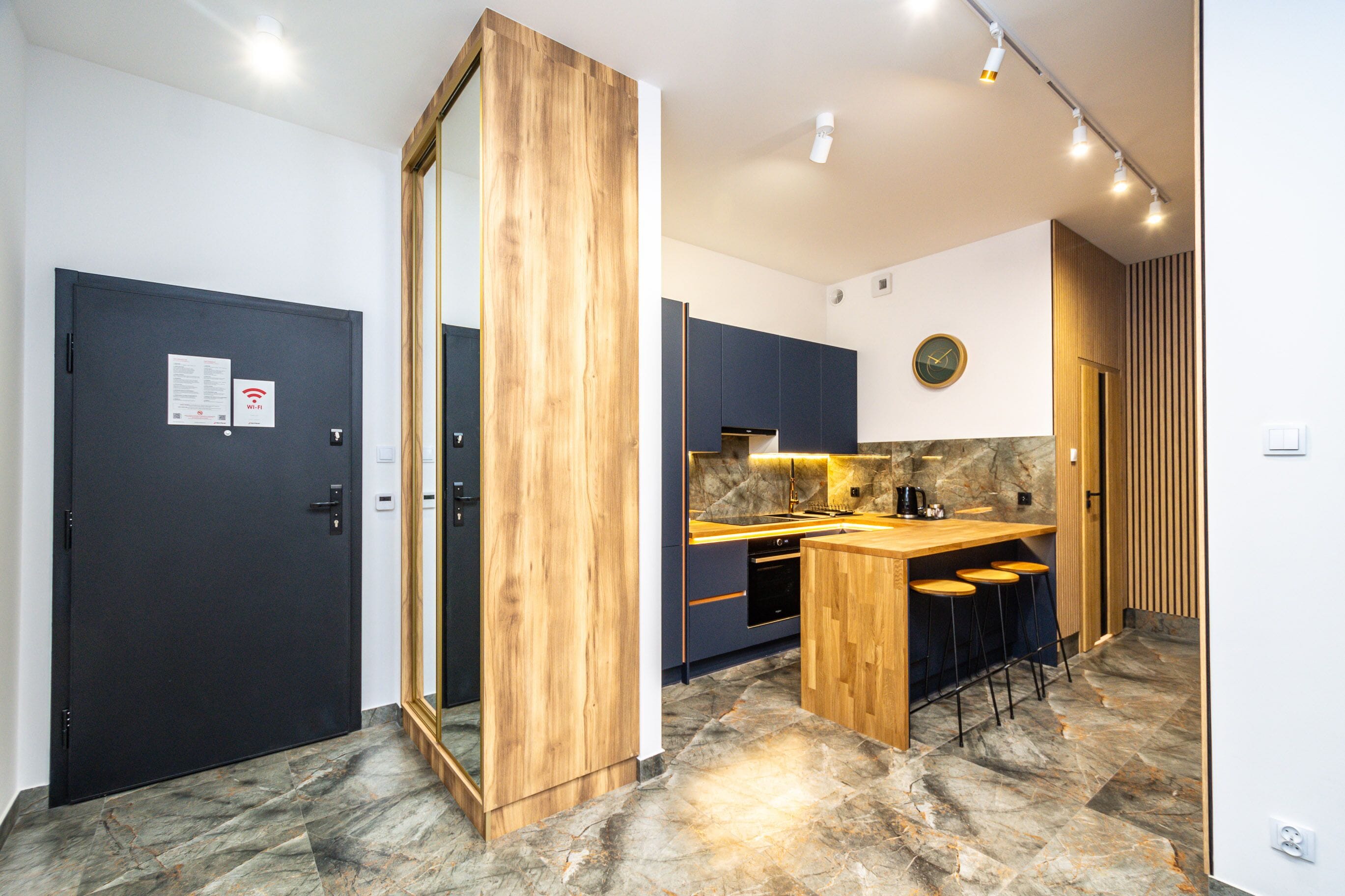 Una cocina moderna con armarios oscuros, una isla de madera y un salpicadero de piedra.