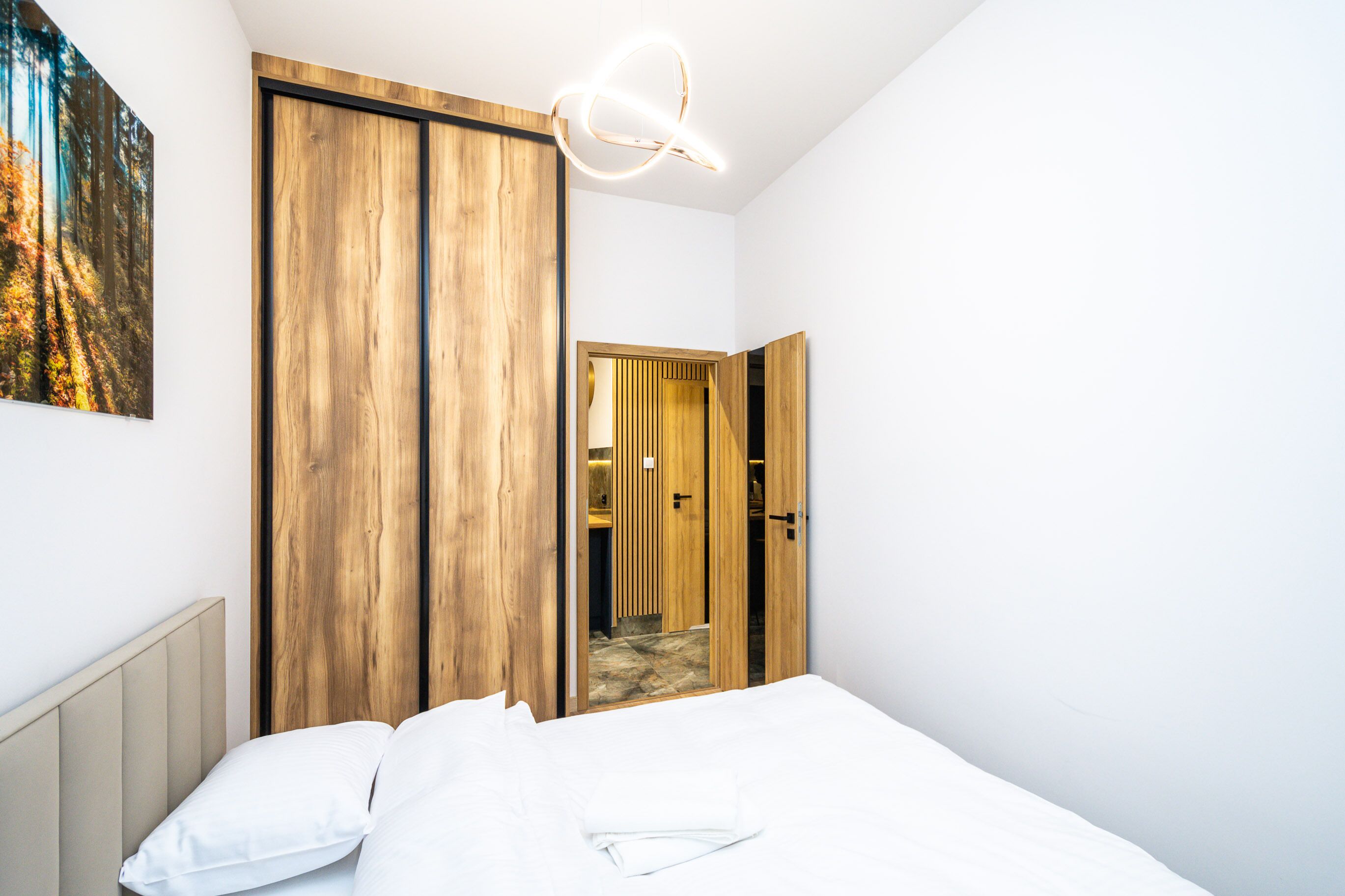 Un dormitorio con cama, un armario de madera y un espejo.