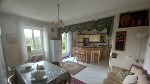 Un vaste espace de vie comprenant une table à manger, un canapé et une cuisine en arrière-plan.