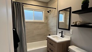 A modern bathroom with a bathtub, a toilet, a sink, and a shower. - Newly Remodeled Monthly Special!!  2 Bd/1Bath Home! (Parma Heights)