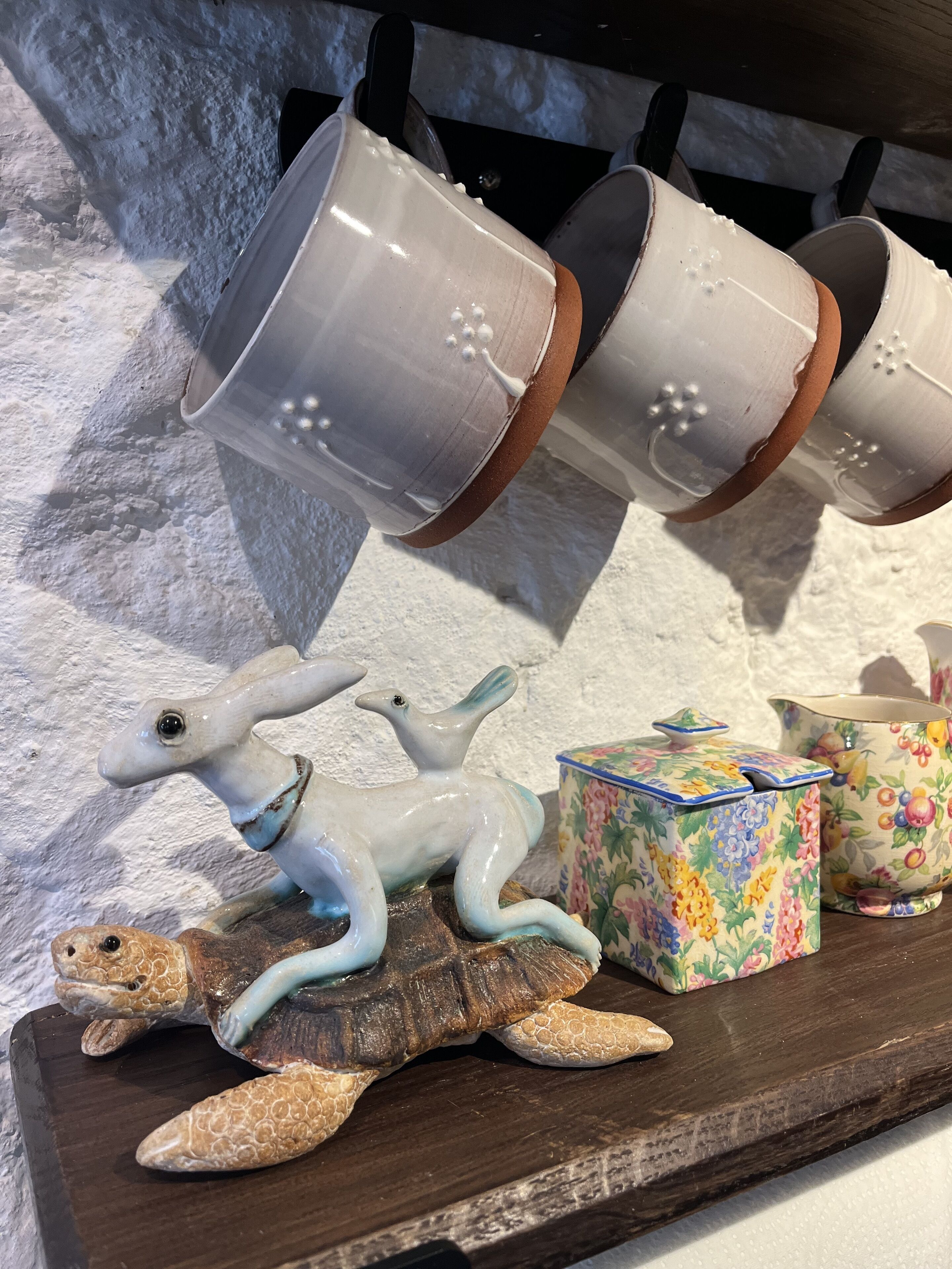 A tray with ceramic cups, a ceramic turtle, and a floral box.