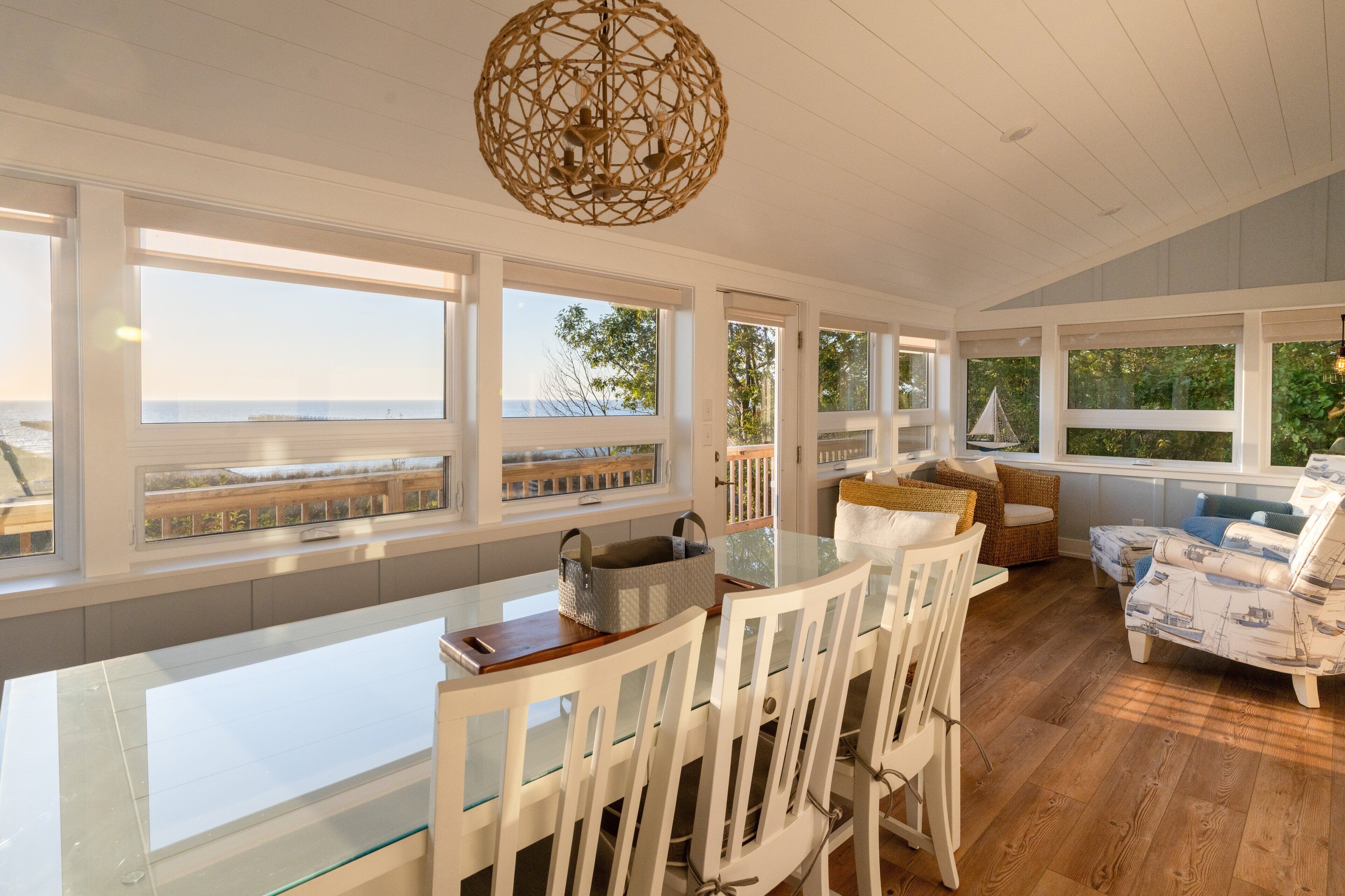A spacious dining area with a glass table and white chairs, overlooking a scenic view.