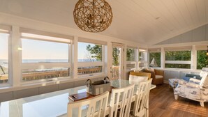 A spacious dining area with a glass table and white chairs, overlooking a scenic view. - Charming Cottage, Private Lake MI Beach (West Olive)