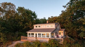 A two-story house with a balcony, surrounded by dense trees. - Charming Cottage, Private Lake MI Beach (West Olive)
