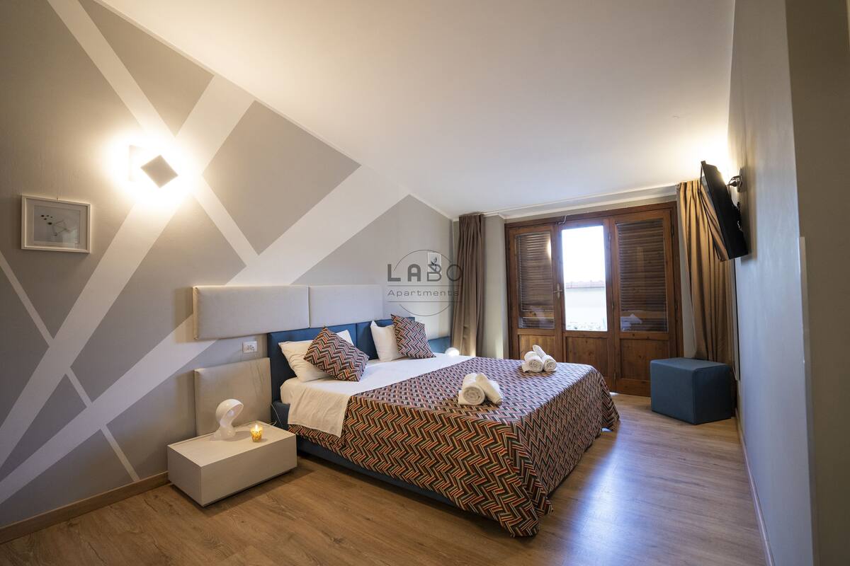 A modern bedroom with a bed, bedside tables, and a television.