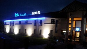 Un hotel con un letrero que dice "ibis budget HOTEL" y una entrada bien iluminada.