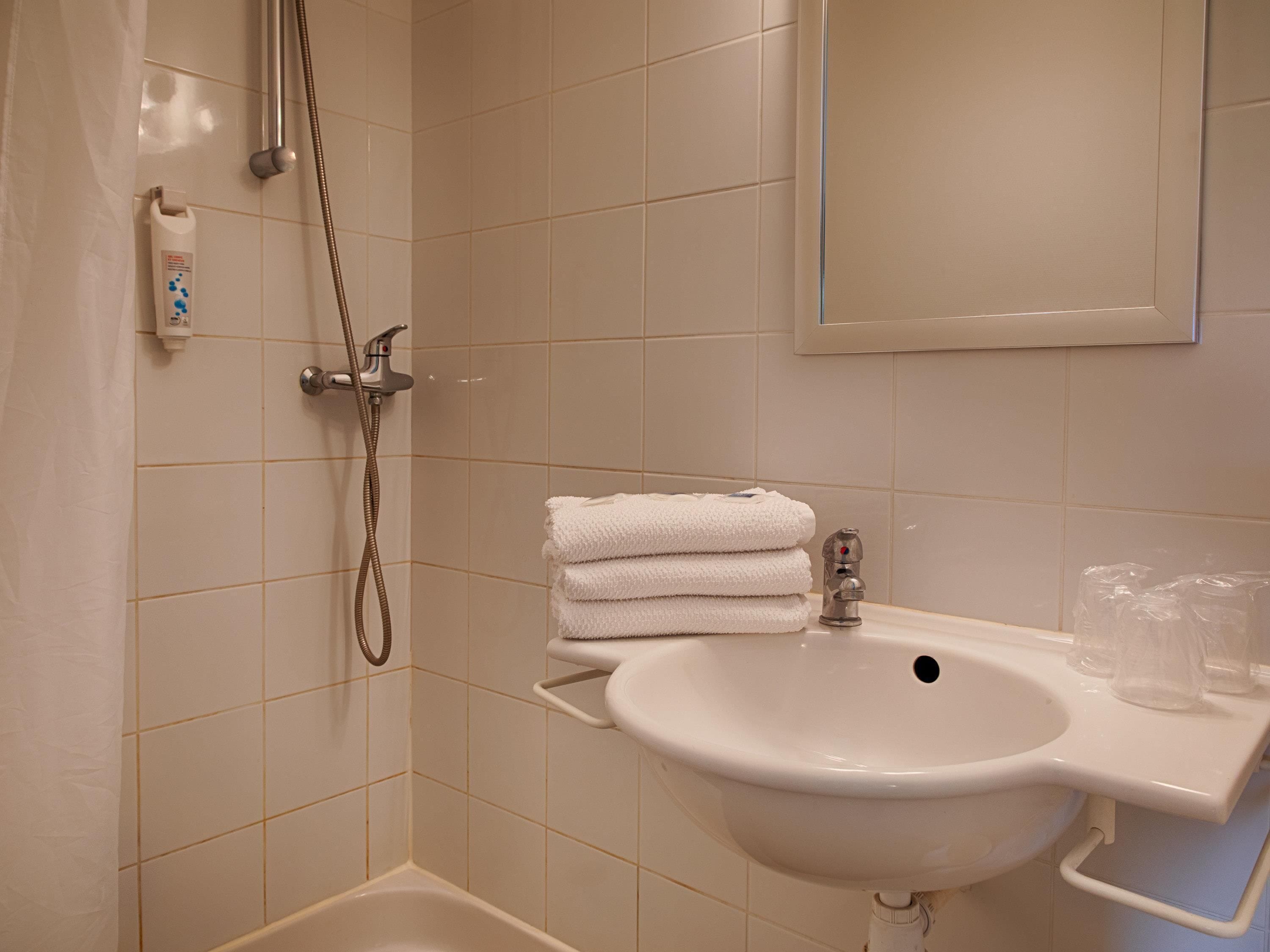 Un baño con lavamanos, espejo y ducha.