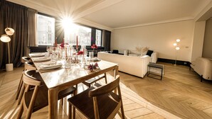 Un espace repas moderne avec une table en bois dressée pour six personnes, un canapé et une petite table d’appoint.