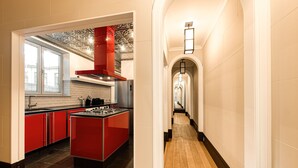 Une cuisine moderne avec des meubles de rangement rouges, un îlot central et une vue sur la ville grâce à de grandes fenêtres.