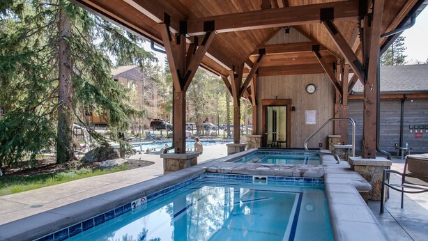 Katettu ulkouima-allasalue, jossa on puinen huvimaja, kivipenkkejä ja näkymä taustalla olevaan rakennukseen.