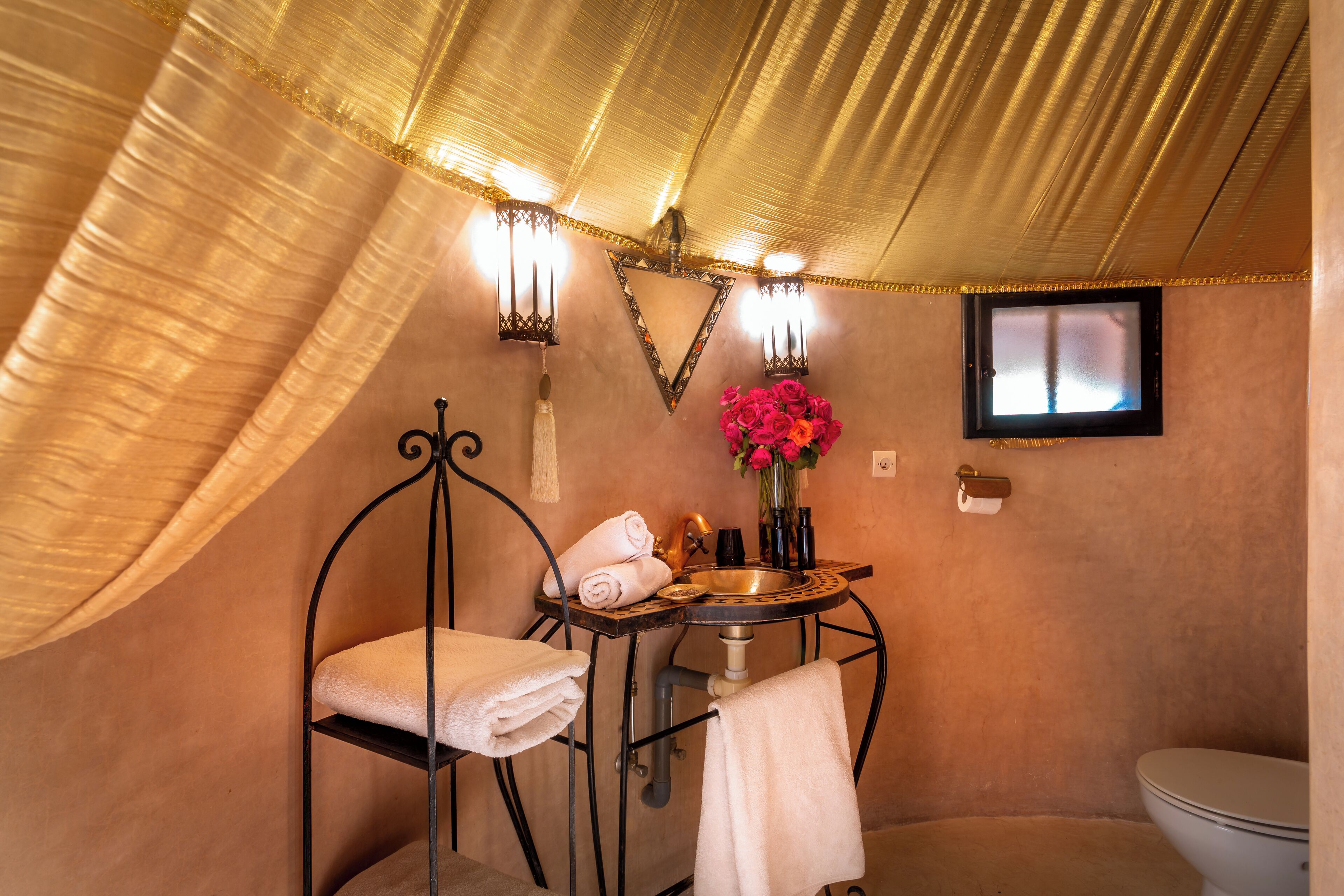 A bathroom with a bathtub, a sink, and a toilet. There are towels and a vase with flowers on the sink.