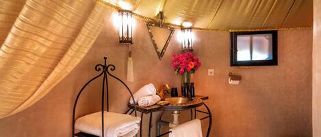 A bathroom with a bathtub, a sink, and a toilet. There are towels and a vase with flowers on the sink.