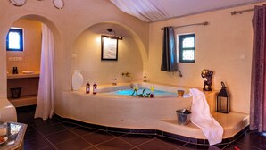 A spacious bathroom with a large bathtub, a vanity with a mirror, and a window providing natural light. - Les Jardins D'Issil Maison d'Hôtes (Sidi Abdallah Ghiat)