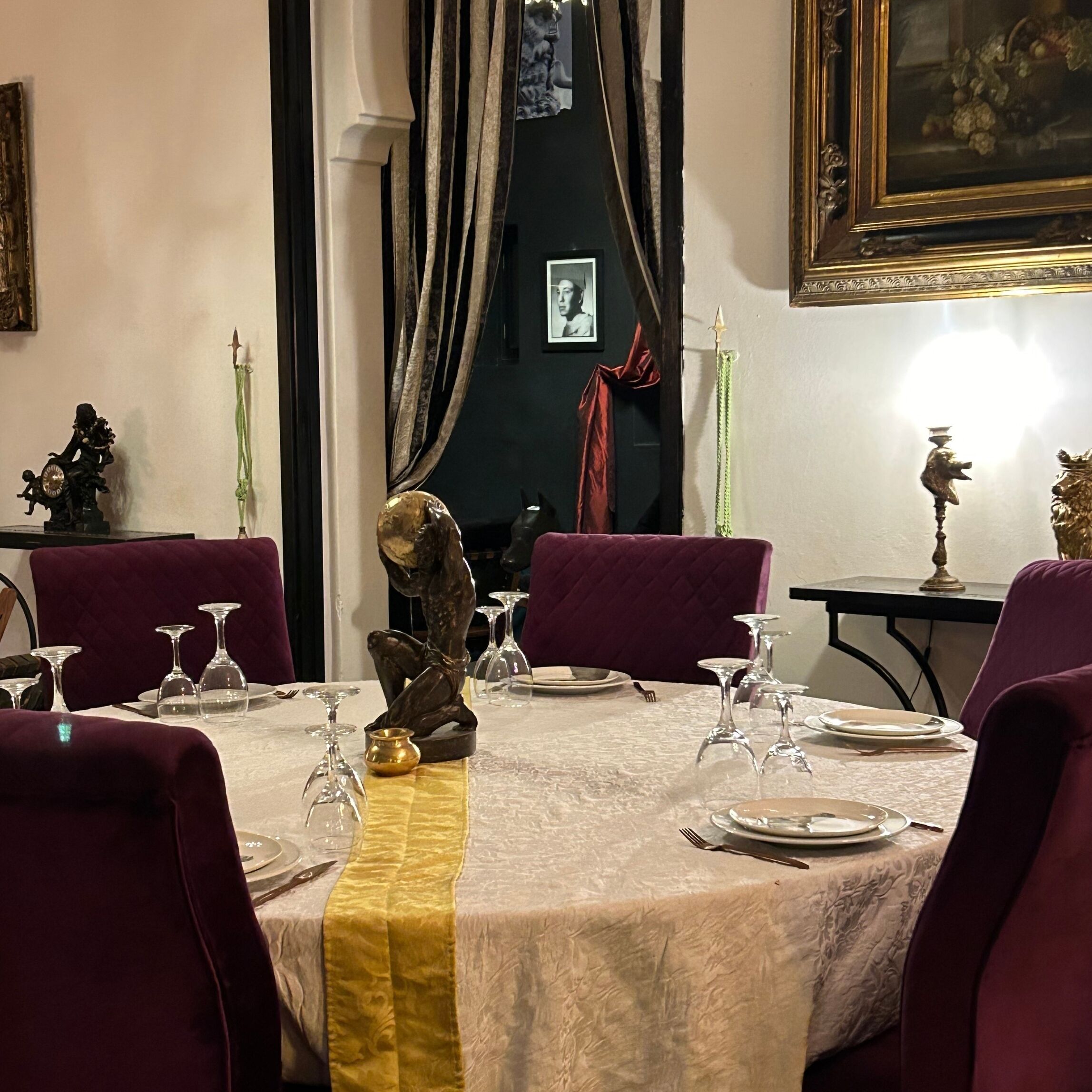 A dining room with a table set for four, featuring a marble tablecloth, purple chairs, and a golden runner.