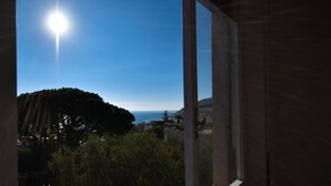A view from inside a building looking out to the sea with a clear sky and a tree in the foreground. - Relax Apartment N 5 by Wonderful Italy (Sanremo)