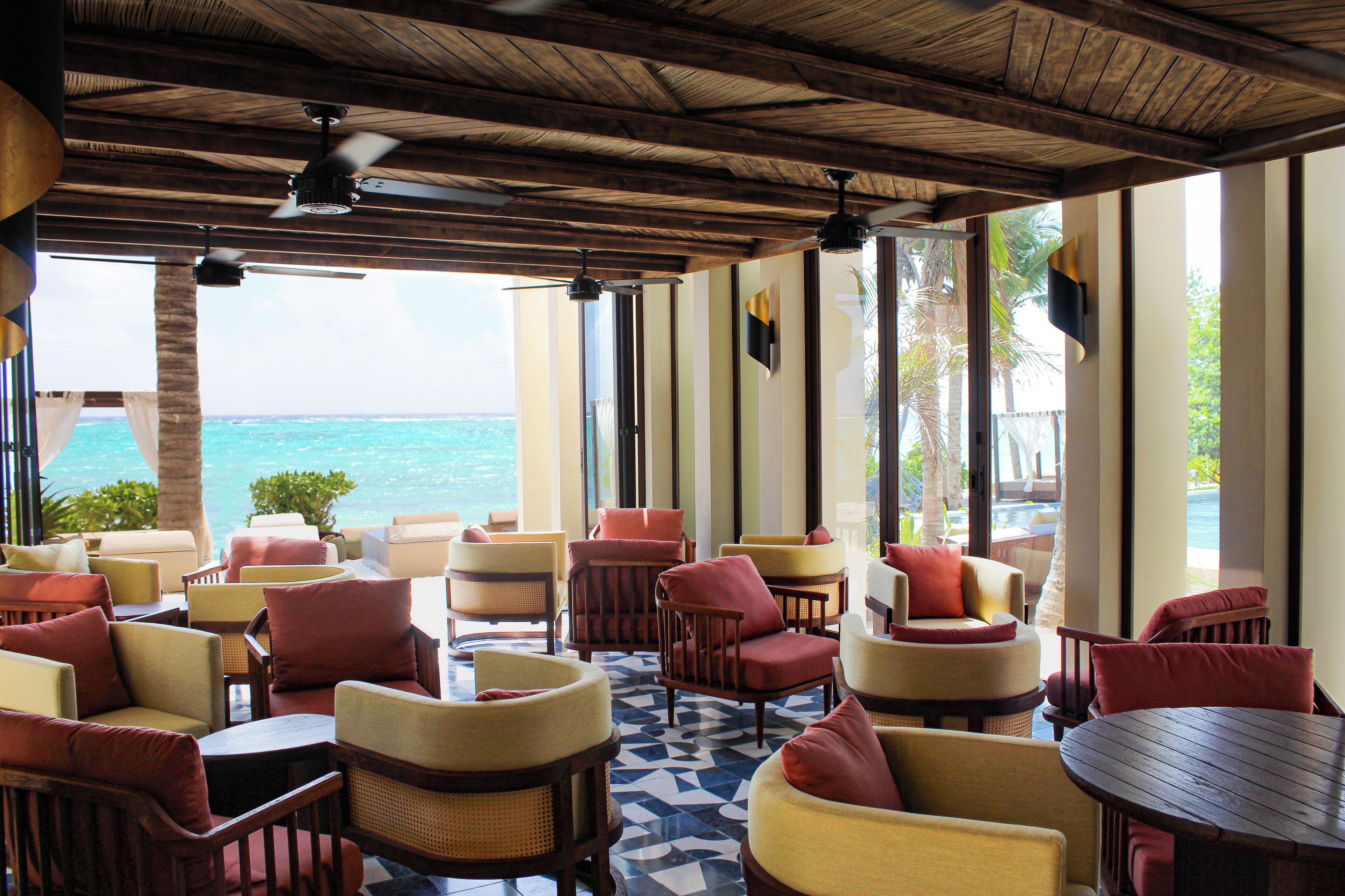 Eine Strandlounge mit verschiedenen Sitzbereichen, großen Fenstern und Blick auf den Ozean.