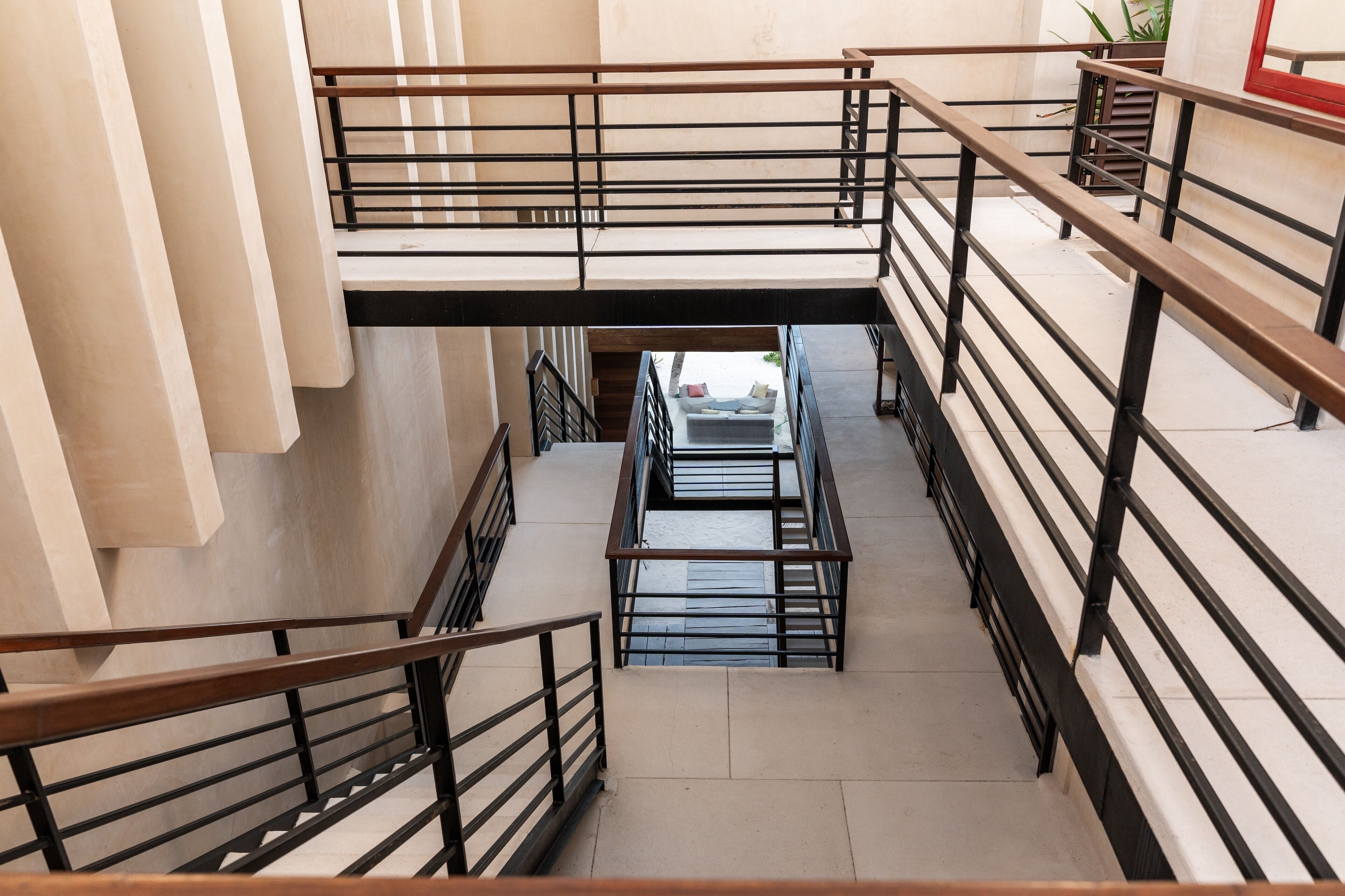 A multi-level interior with a central staircase, metal railings, and a view of a living area below.