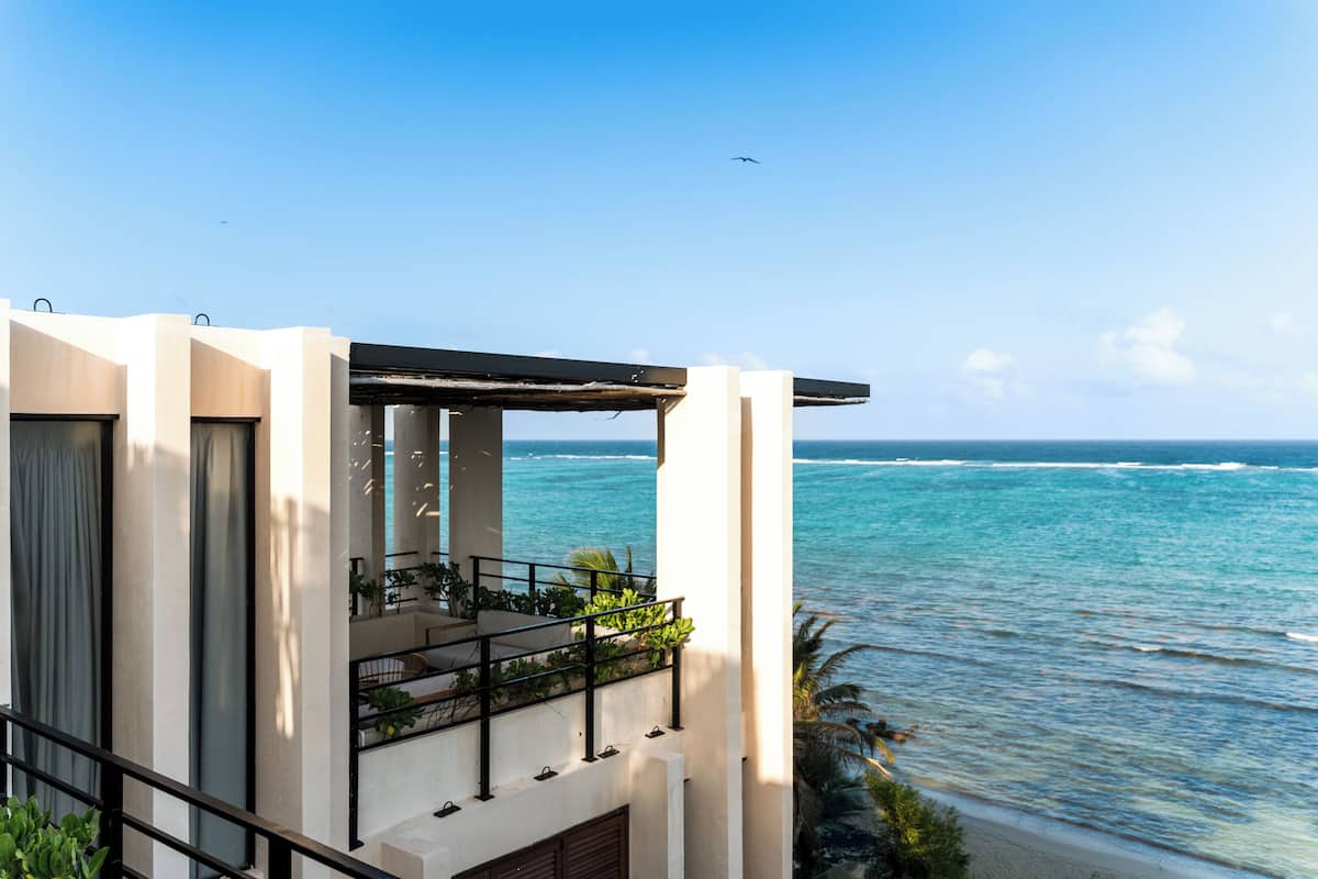 A modern building with a balcony overlooking a beach.