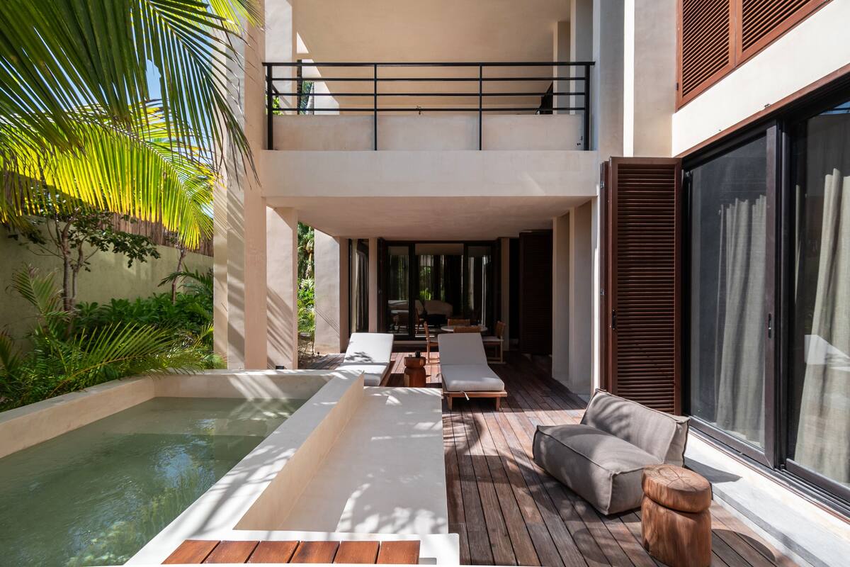 A modern outdoor pool area with a hot tub, lounge chairs, and a wooden deck.