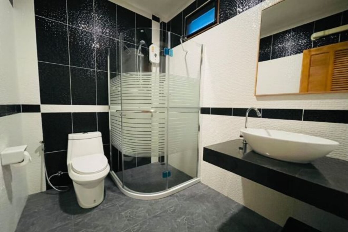 A modern bathroom with a toilet, a glass shower enclosure, and a sink.