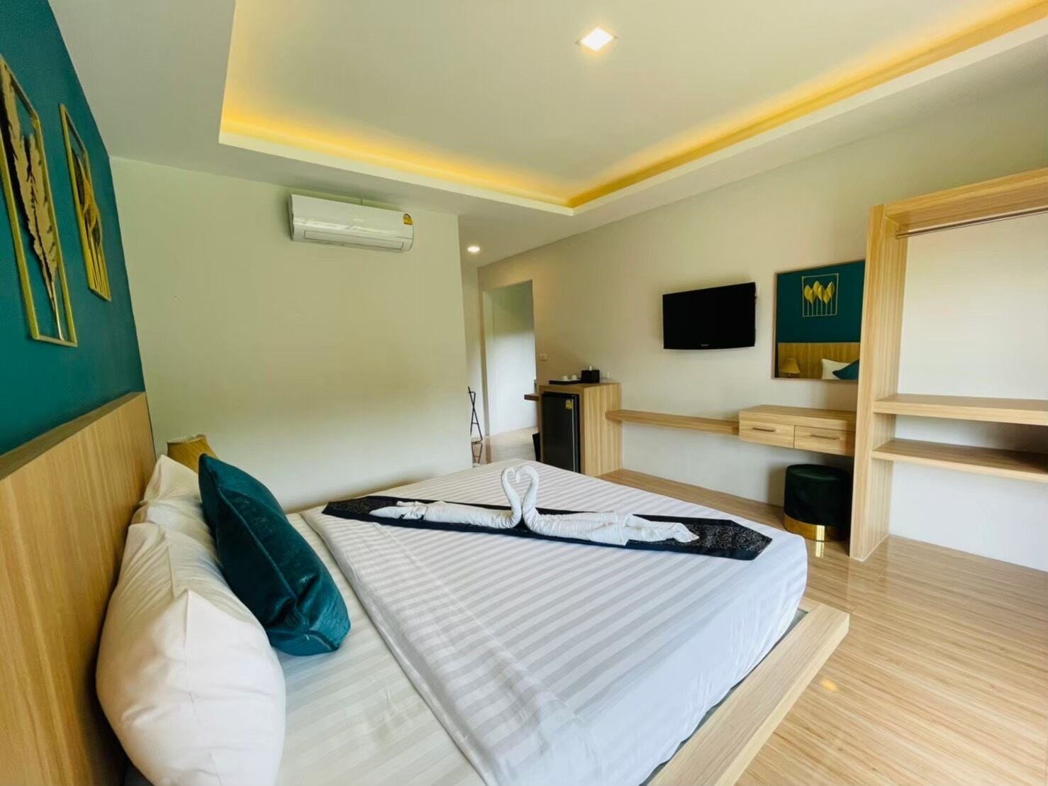 A hotel room with a bed, a desk, a TV, and an air conditioning unit.