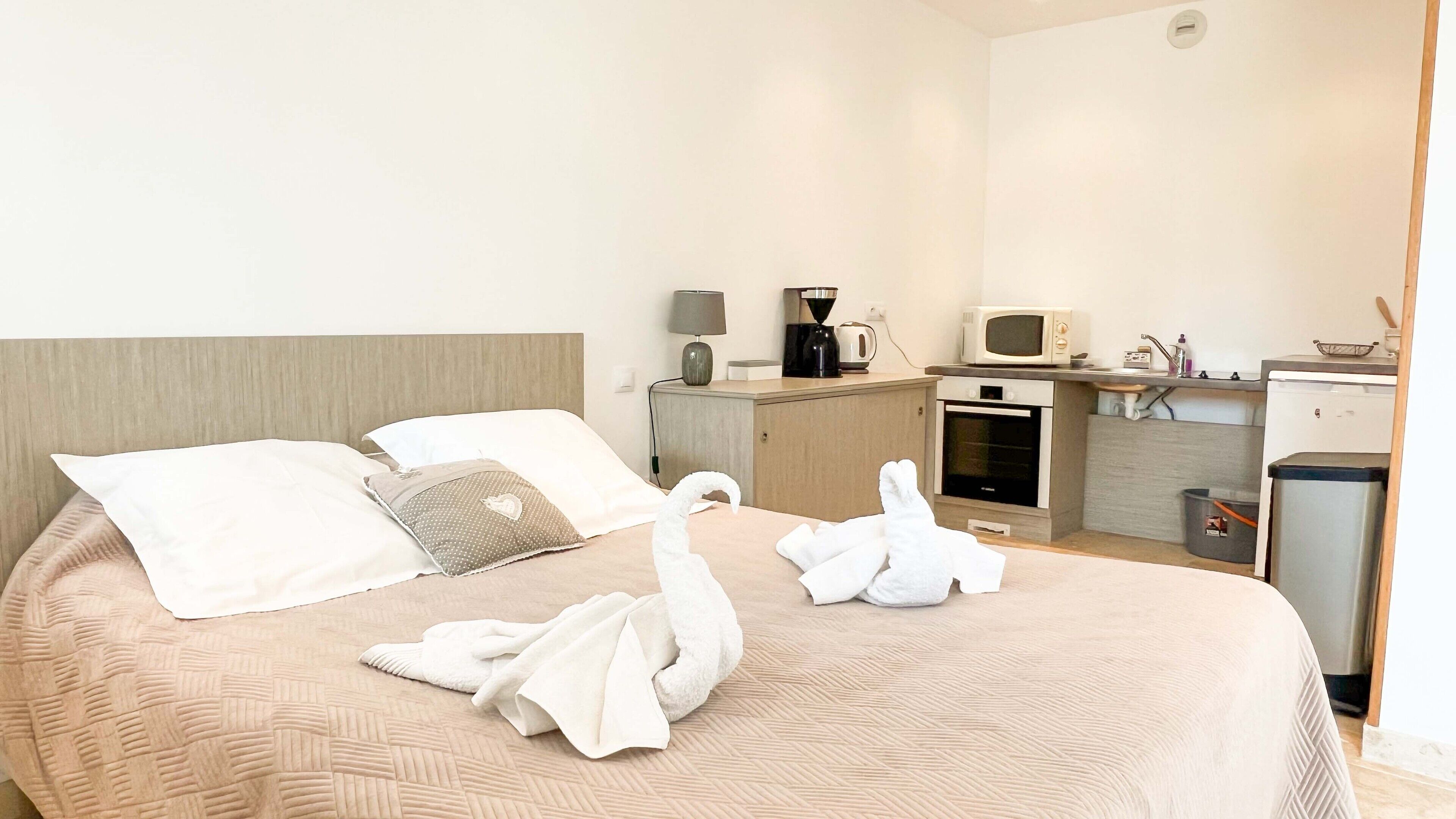 Ein Hotelzimmer mit einem Bett, einer kleinen Küchenzeile und einem Mülleimer.