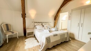 Een slaapkamer met een bed, een stoel, een kledingkast en een houten balk.