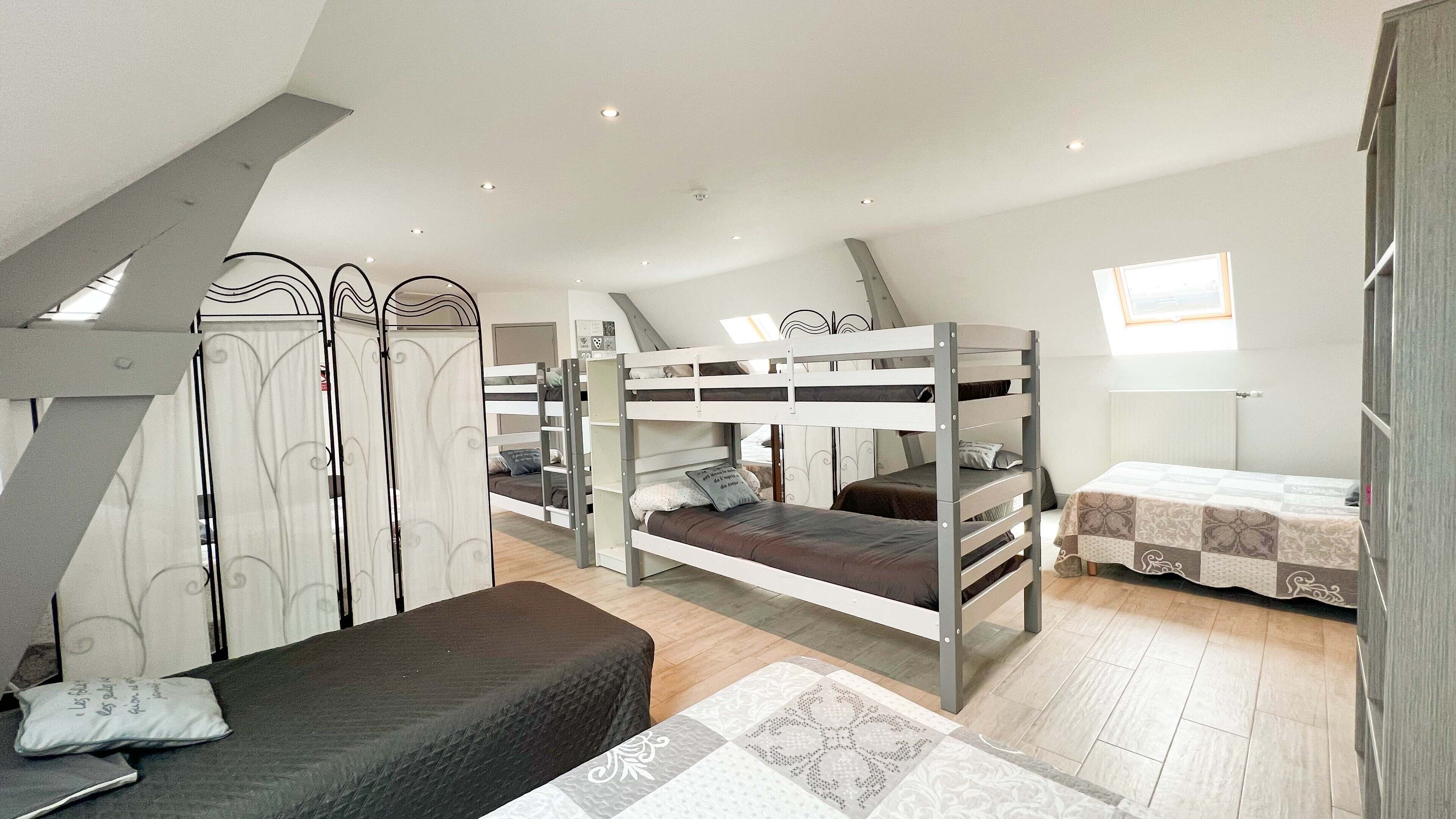 A dormitory room with bunk beds, a desk, and a window.