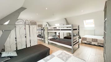 A dormitory room with bunk beds, a desk, and a window.