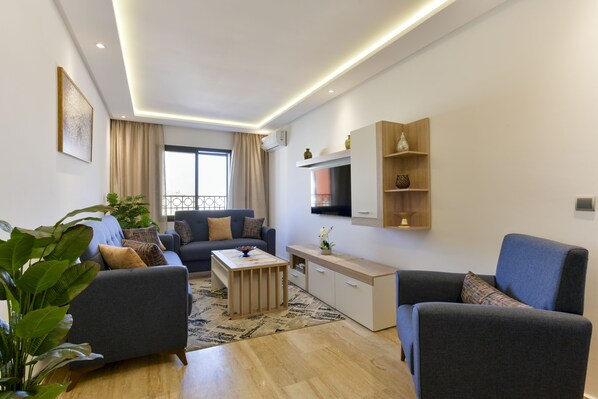 A modern living room with a sofa, coffee table, and a TV mounted on the wall. - Charming Cozy Apartment - Rabat Center - Free parking & AirC & Fiber internet (Rabat)