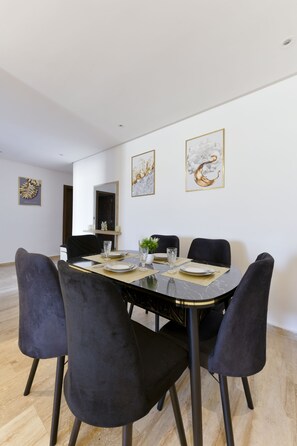 A dining area with a round table, four chairs, and artwork on the walls. - Charming Cozy Apartment - Rabat Center - Free parking & AirC & Fiber internet (Rabat)