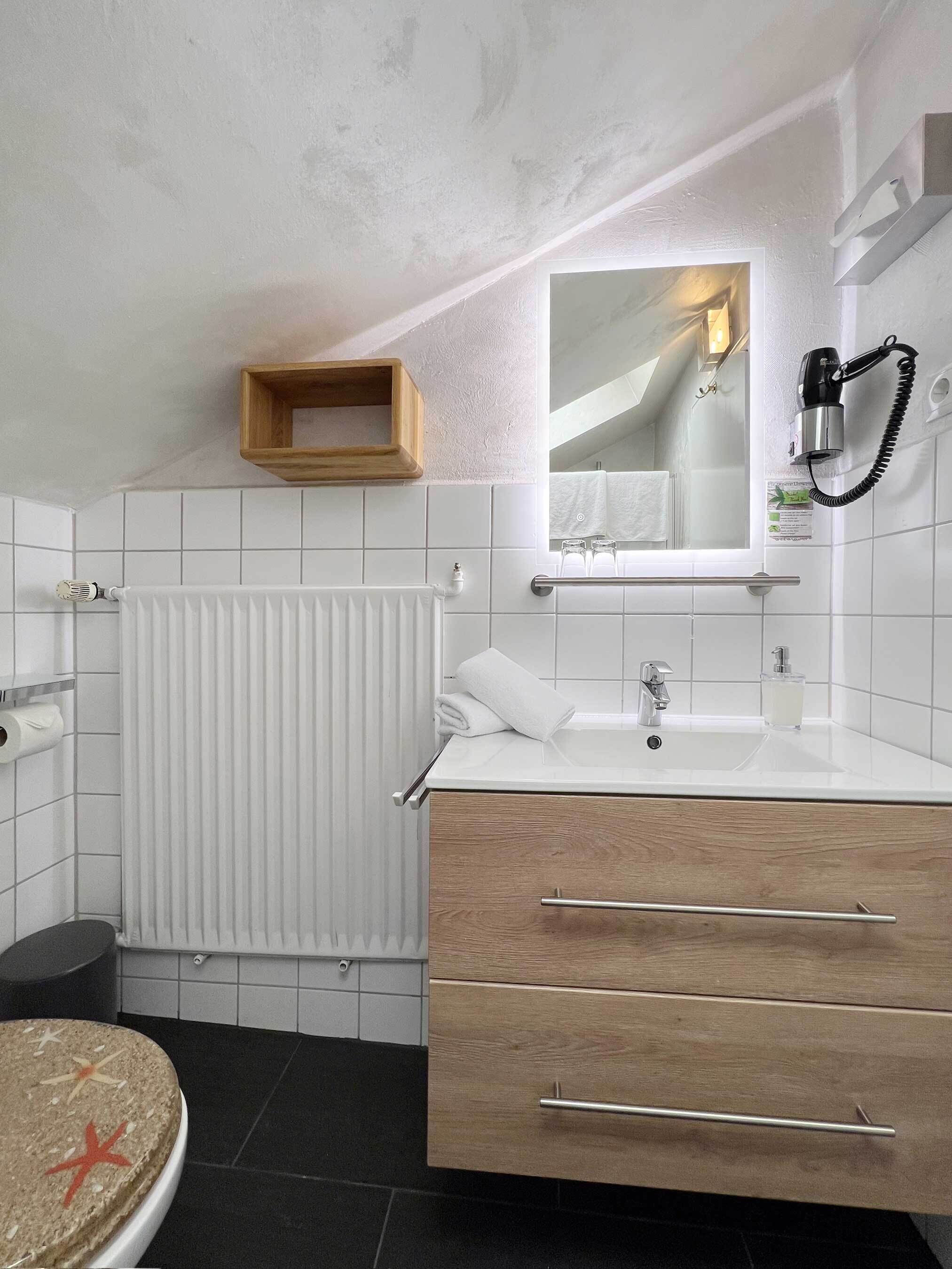 A modern bathroom with a white sink, wooden vanity, and a towel rack.