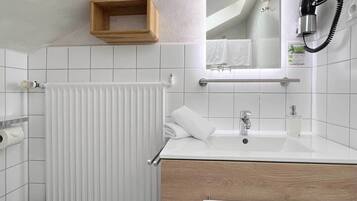 A modern bathroom with a white sink, wooden vanity, and a towel rack.