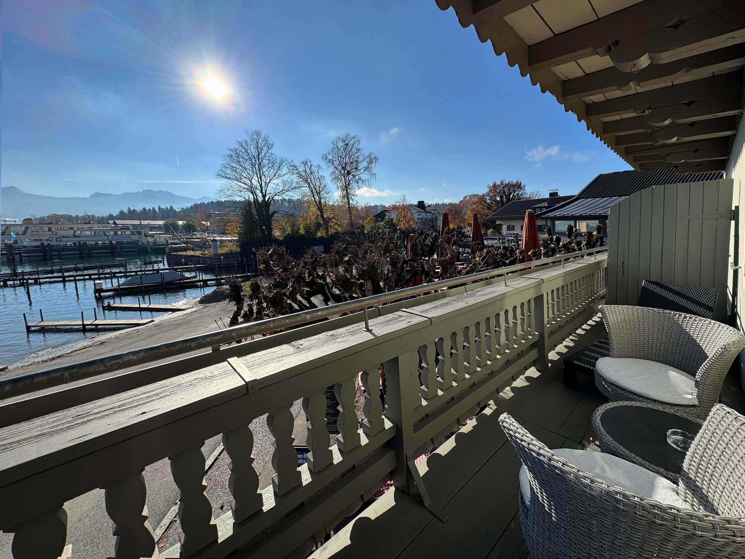 A balcony with wicker furniture overlooking a marina with boats and a dock.