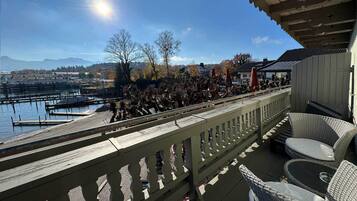 A balcony with wicker furniture overlooking a marina with boats and a dock.