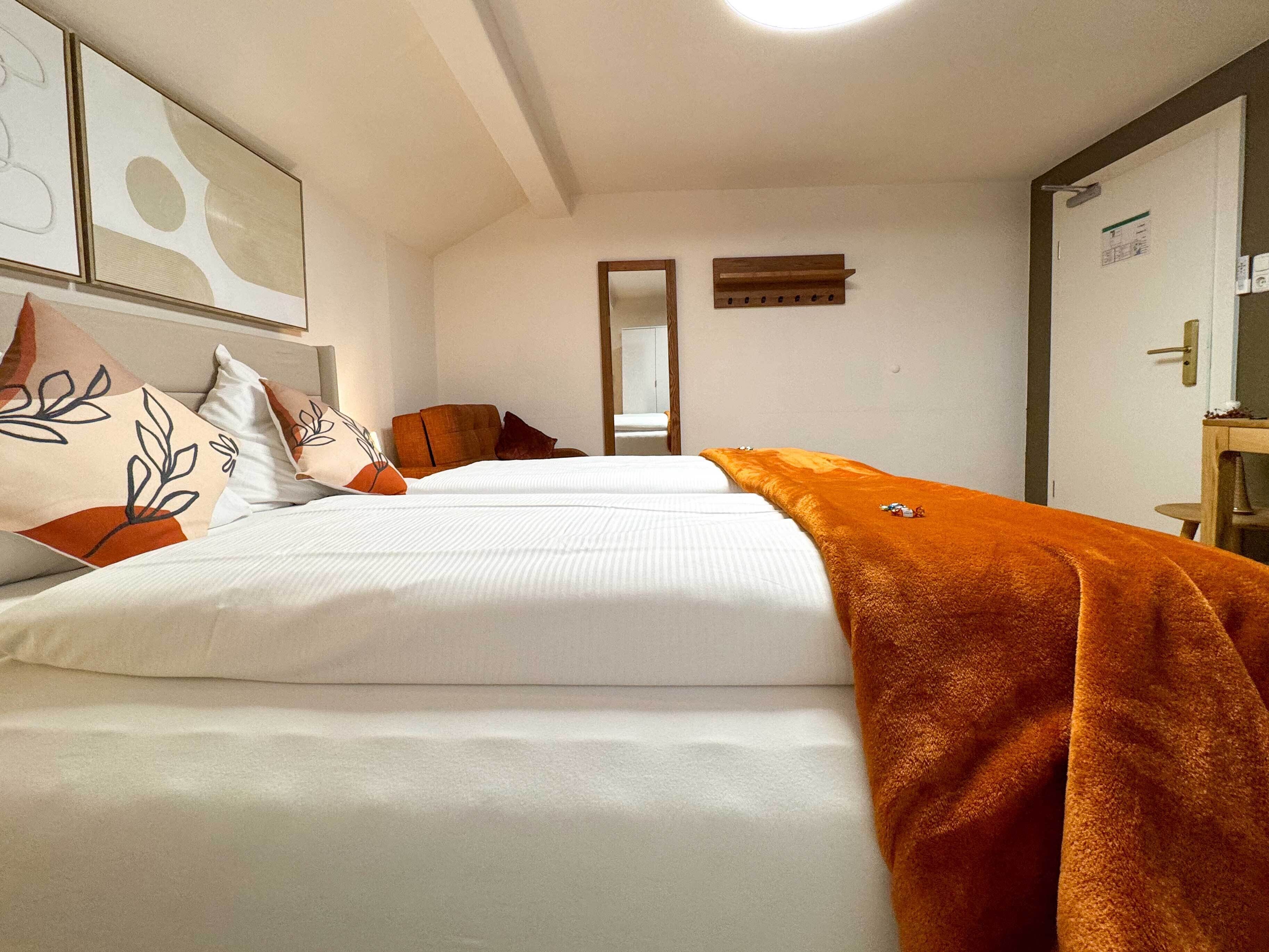 Habitación de hotel con dos camas, un espejo, un aparador de madera y una puerta con un cartel.