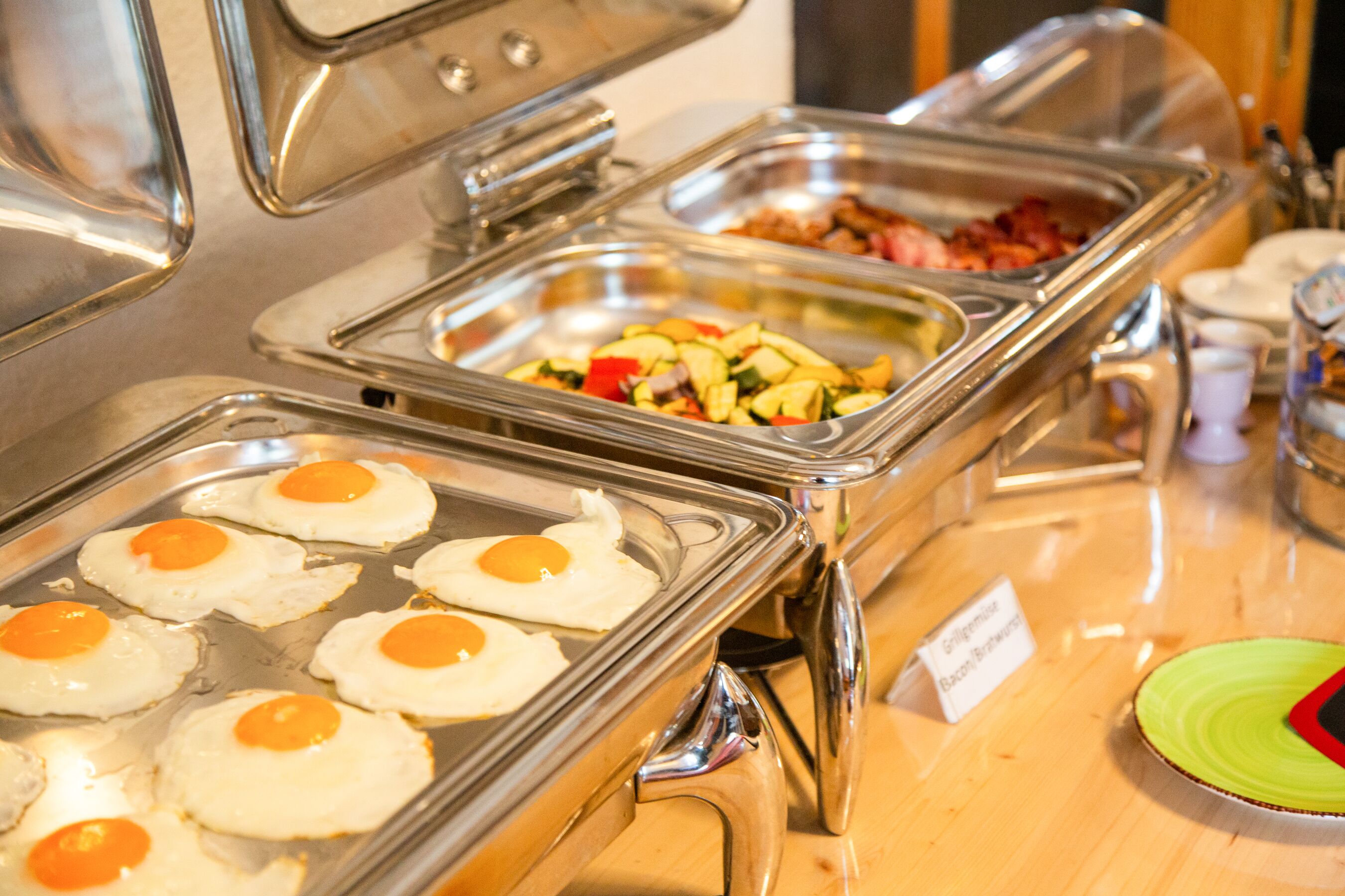 A buffet with various food options including eggs, bacon, and vegetables.