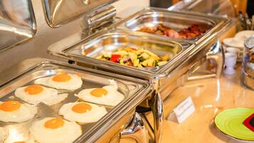 A buffet with various food options including eggs, bacon, and vegetables.