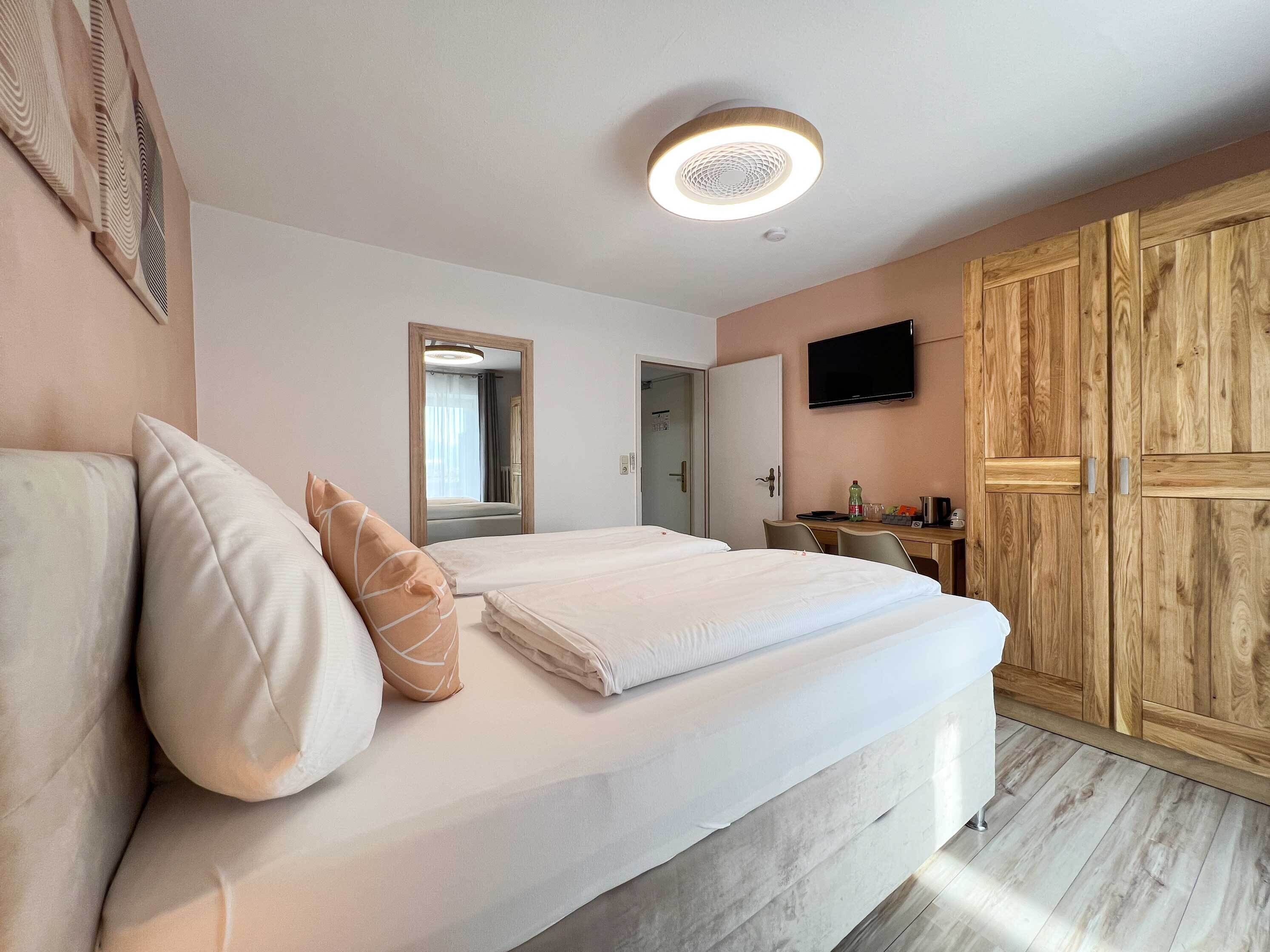 Una habitación de hotel con cama, escritorio, televisor y armario.