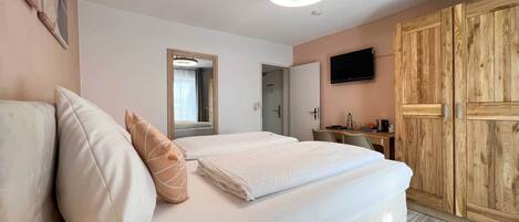 Una habitación de hotel con cama, escritorio, televisor y armario.